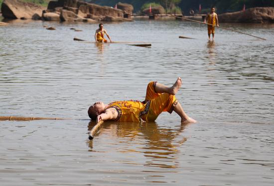A man lies on bamboo poles in a river in Chishui, Guizhou province, on Tuesday. Local people began to use bamboo poles as a means of transport about 1,000 years ago. The technique was added to the provincial intangible cultural heritage list in 2009. (Photo by Yang Jun/China Daily)