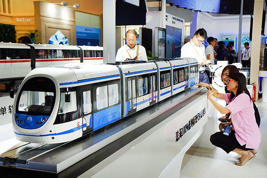 Visitors look at the latest models of urban rail trains shown at the International Urban Rail Exhibition in Beijing. (Photo/Xinhua)