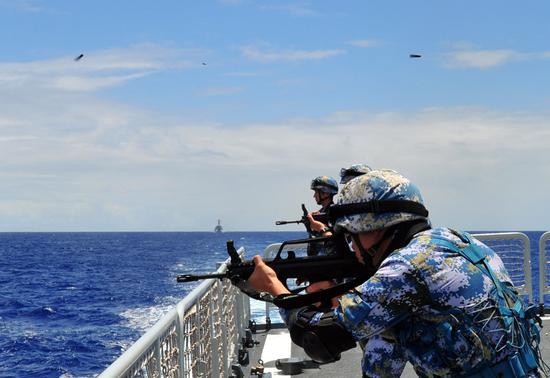 Soldiers open fire on board the guided-missile destroyer Haikou during an international maritime exercise. (Photo by SHAO LONGFEI/FOR CHINA DAILY)