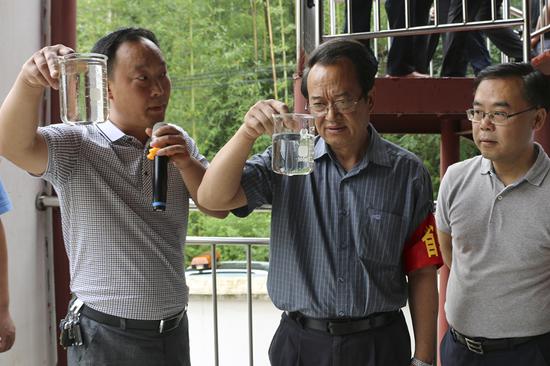 Meng Qiliang, vice-chairman of the Guizhou Committee of the Chinese People's Political Consultative Conference (center), and Tan Hai, mayor of Chishui, Guizhou Province (right), check the water quality of the Chishui River. (Provided to China Daily)