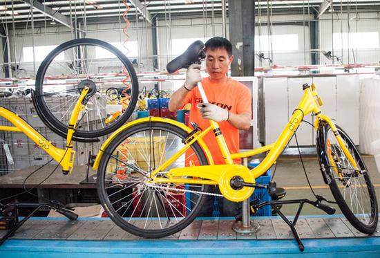 A worker assembles an Ofo bike at a plant in Tianjin. (Photo by Wang Weiwei/For China Daily)