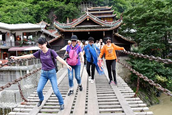 Tourists negotiate the Luding Bridge across the Dadu River in Southwest China's Sichuan Province. Associated with the Long March, the site is popular on the red tourism circuit. （Photo by Wang Huabin/For China Daily）