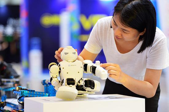 A visitor plays with a small robot at a science and cultural innovation exposition held in the China (Fujian) Pilot Free Trade Zone. (Photo/Xinhua)