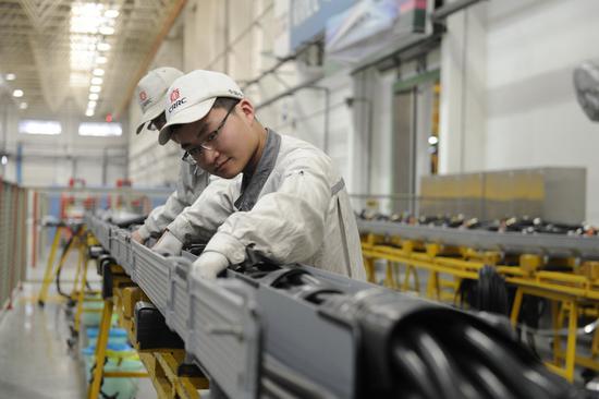 CRRC employees operate an assembly line of the company in Qingdao, Shandong province. （Photo by Zhang Jingang/For China Daily）