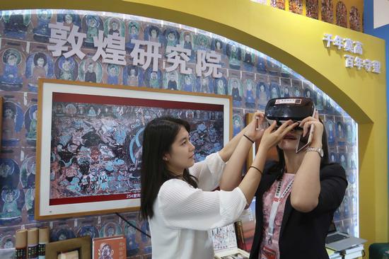 A visitor experiences the frescoes of the Dunhuang Mogao Grottoes using virtual reality at an exhibition in Shanghai. (Provided to China Daily)