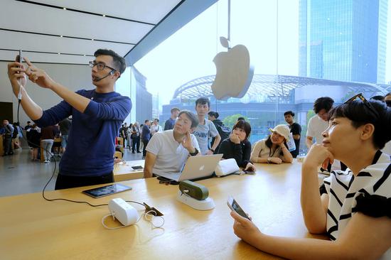 Customers check out iPhones at an Apple store in Guangzhou, capital of Guangdong Province. (Photo by Li Zhihao / for China Daily)