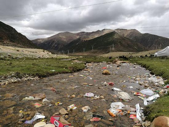 Garbage pollutes a river along the Sichuan-Tibet Highway. (Lin Peng/For China Daily)