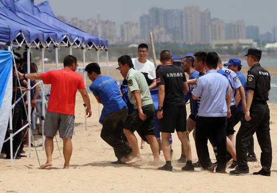 Rescuers escort the body of an 8-year-old girl who drowned with her twin sister in Qingdao, Shandong Province. The girls, who traveled with their mother from Beijing, went missing on Sunday afternoon while they were playing on a beach in the city's Huangdao district. (Photo provided to China Daily)