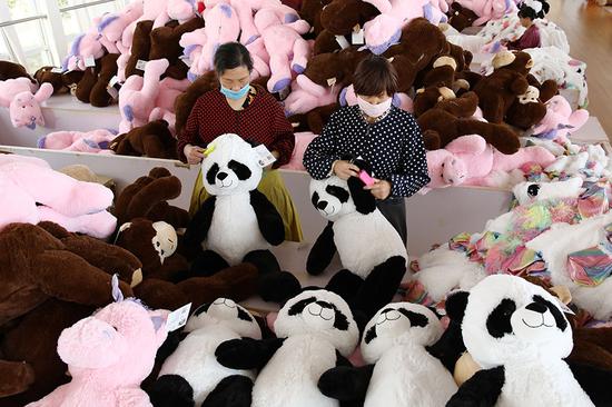 Workers make stuffed toys, which will be exported to Europe and the United States, at a factory in Lianyungang, JiangsuPprovince. (Photo by Si Wei and Zhang Jingang/for China Daily)