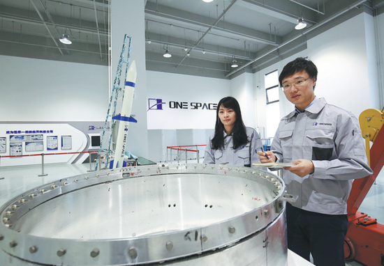 OneSpace Technology CEO Shu Chang (right) works at the private rocket company's exhibition room in Beijing. (Photo/China Daily)