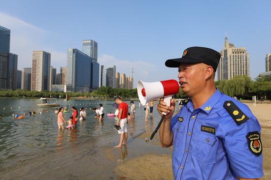 An urban management officer warns visitors of danger at Tian'e Lake in Hefei, Anhui Province. (Photo/CHINA DAILY)