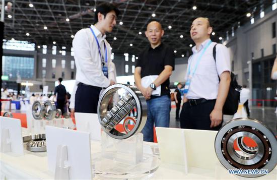 A staff member (L) introduces bearing products to visitors during the Matchmaking Meeting for Exhibitors & Buyers of High-end Intelligent Equipment Exhibition Area for the 2018 China International Import Expo (CIIE) in Shanghai, east China, Aug. 8, 2018. Shanghai is scheduled to host the first CIIE from Nov. 5 to 10. (Xinhua/Fang Zhe)