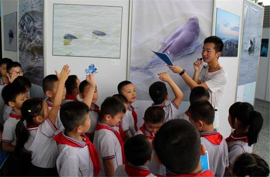 A volunteer explains protection measures for the finless porpoise to primary school students in Nanjing, capital of Jiangsu Province. (ZHANG KUN FOR/CHINA DAILY)