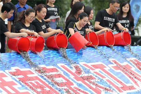 Nanjing residents send various types of young fish into the Yangtze River to restore the food chain by increasing the fish population, as part of a campaign to protect the finless porpoise. (YANG BO/CHINA NEWS SERVICE)