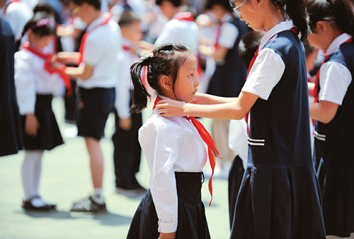 A student from sixth grade adjusts a red scarf on a first grade student at Shanxi Experimental Primary School, Taiyuan, May 31. More than 400 students in first grade put on red scarves for the day –– a symbol of them joining the Young Pioneers of China movement, as part of the upcoming International Children’s Day on June 1. (Photo/Shanxi Daily)