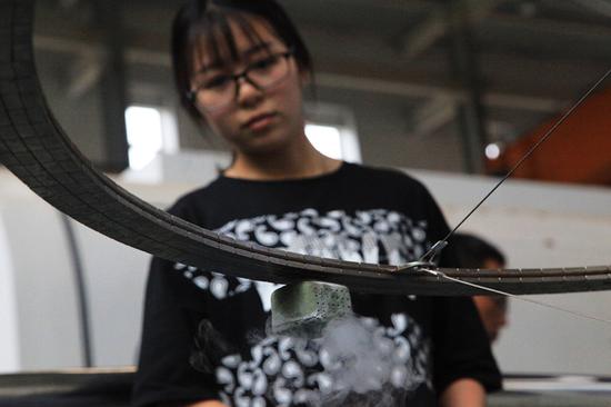 A Southwest Jiaotong University student displays a model of a high-temperature superconductor maglev. (YI HAN/FOR CHINA DAILY)