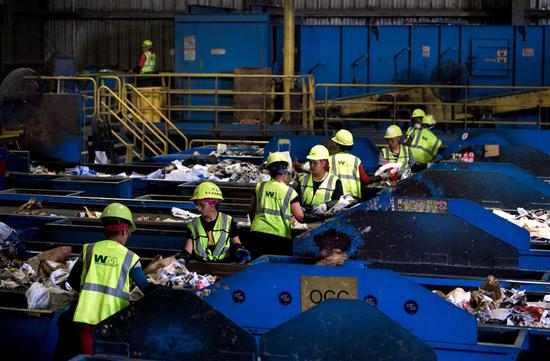 Workers sort material for recycling at the Waste Management Material Recovery Facility in Elkridge, Maryland, United States, in June. For months, this major recycling facility for the Greater Baltimore-Washington Area has been paying to get rid of huge amounts of paper and plastic it would normally have sold to China. (Photo provided to China Daily)