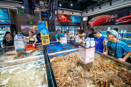 Shoppers buy seafood at Hema Fresh in Guangzhou, Guangdong Province. （Photo provided to China Daily）