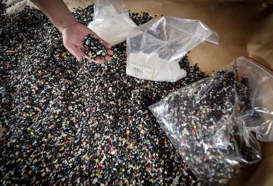 A customs officer in Shenzhen, Guangdong Province, inspects plastic waste that was to be smuggled into China from Belgium. (Photo/Xinhua)