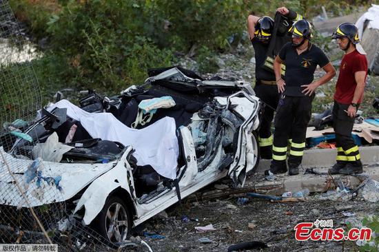 Firefighters stand next to a crushed car at the collapsed Morandi Bridge site in the port city of Genoa, Italy August 14, 2018.  (Photo/Agencies)