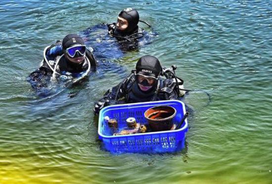 Zhang Xudong (the one in front) and two volunteers emerge from the water with a basket of waste they collected underwater. (Photo/Legal Evening News)