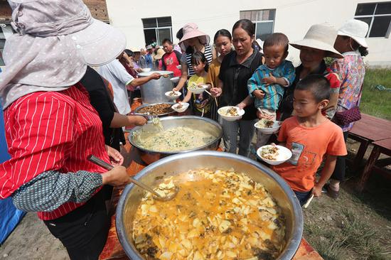 Villagers receive food at a shelter after two separate magnitude 5.0 earthquakes jolted Sijie township, Tonghai county, in Yunnan province on Monday and Tuesday. Eighteen people were reported injured and more than 33,000 evacuated, local authorities said. (YANG ZHENG/FOR CHINA DAILY)