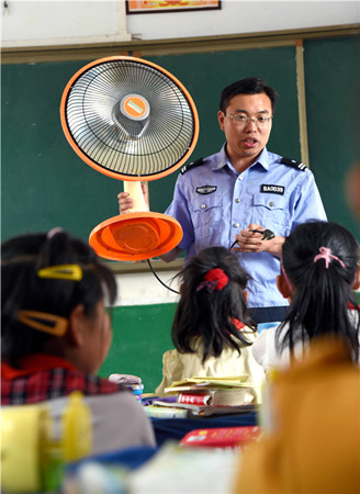A security guard demonstrates the safe use of electricity to students in Zaozhuang, Shandong Province. (LIU MINGXIANG/FOR CHINA DAILY)