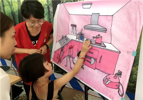 A girl tries to identify potential dangers in a kitchen during a safety lecture in Shanghai. (ZHOU WENTING/CHINA DAILY)