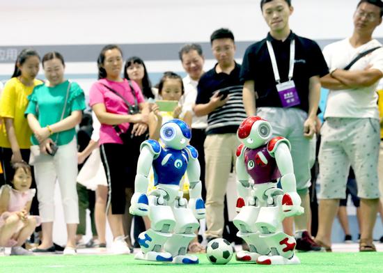 Two robots play football at the 2018 World Robot Conference in Beijing, Aug。 15, 2018.（Photo/China Daily）