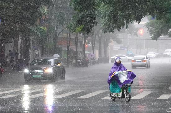 A woman rides an electric bike in the rain in Shanghai on August 16, 2018. (Photo/Shine.cn)