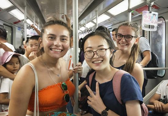 Catalina Carrion Sierra (left) from King's College London and Agne Bendaraviciute (right) from Bournemouth University take a subway to the Bund during their visit in Shanghai, accompanied by volunteer Peng Shasha (middle) from East China Normal University. (ZHENG YAJING/FOR CHINA DAILY)