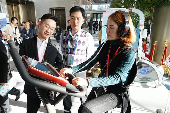 A visitor tries an intelligent bicycle at the 2018 National Sports Industry Development Conference held in Xiamen, Fujian Province. (Photo/Xinhua)