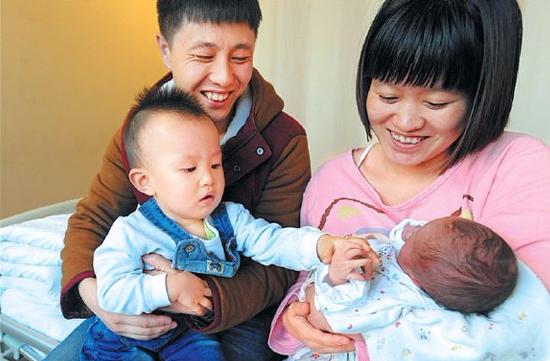 A couple both born after 1990 hold their children, an infant daughter and her 18-month-old elder brother, in Shenyang, Liaoning Province, on Jan. 3, 2016. (Photo by Lihao/For China Daily)