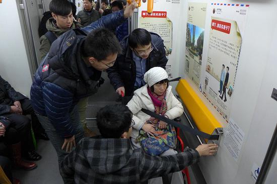 Volunteers help a disabled woman use a wheelchair lock on a subway train in Shenyang, Liaoning Province. (ZHAO JINGDONG/FOR CHINA DAILY)