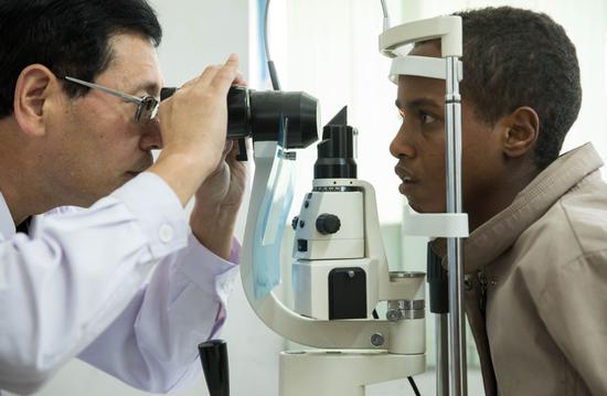 A Chinese ophthalmologist examines a patient at China-Ethiopia Friendship Hospital in Addis Ababa, Ethiopia, on Friday as part of a yearlong free assistance project. A Chinese medical team went to Ethiopia last year to carry out the program. （Photo/Xinhua）