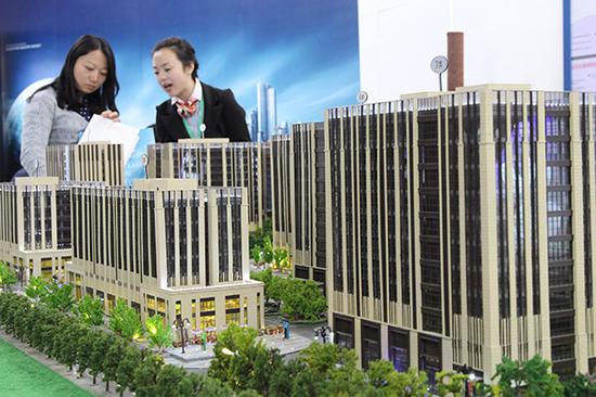 A salesperson presents a housing project at a real property exhibition in Beijing. (Photo provided to China Daily/)
