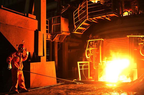 A worker checks molten steel at an iron and steel plant in Dalian, Northeast China's Liaoning province. (Photo by Liu DebinFor China Daily)