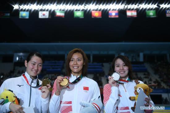 Liu Xiang (C) of China celebrates during the awarding ceremony after women's 50m backstroke final of swimming at the 18th Asian Games in Jakarta, Indonesia, Aug. 21, 2018. Liu won the gold with 26.98 seconds and set a new world record. (Xinhua/Li Xiang)