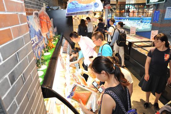 Consumers pick imported salmon fillets from a freezer at a Hema Fresh store in Shanghai. (Photo provided to chinadaily.com.cn)