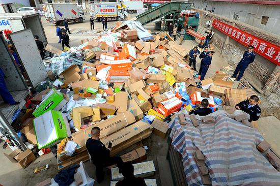 Officers from the Chengguan district branch of the Lanzhou Administration for Industry and Commerce in Gansu province destroy counterfeit goods they seized last year.(Photo by Pei Qiang and Niu Jing/for China Daily)