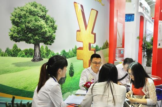 Visitors discuss loan policies during an industry expo in Shanghai. (Photo provided to China Daily)