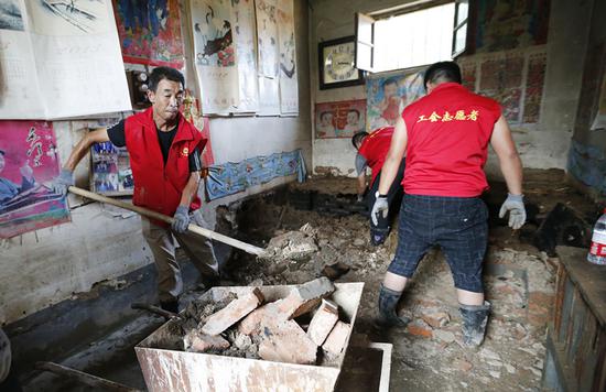 Volunteers help cleanse a villager's flooded home in Shouguang, Shandong province, on Friday. CHINA DAILY