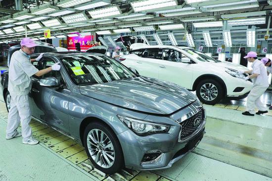 Workers check up cars at an assembly line of Dongfeng Nissan in Xiangyang, Hubei Province. (Photo provided to China Daily)