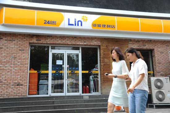 Two pedestrians pass by a closed store of Linjia, a Beijing-based convenience store chain, on Aug. 2, 2018. (Photo provided to China Daily)
