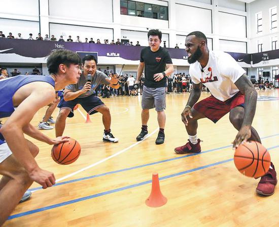LeBron James faces off against a Chinese student during a dribbling drill at the High School Affiliated to Shanghai Jiao Tong University on Sunday. (Photo provided to China Daily)