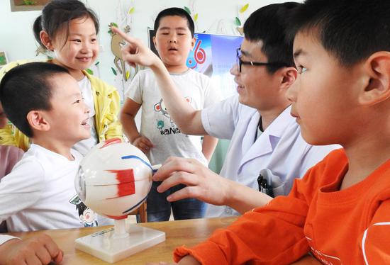 A medical expert from a hospital in Lianyungang, Jiangsu Province, briefs kindergartners on how to protect eyesight and prevent myopia during a health campaign in June. (Photo by Geng Yuhe/For China Daily)