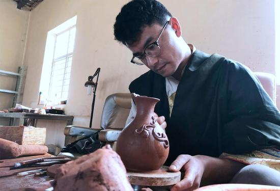 Losang Shepa, the 26-year-old son of State-level inheritor Dadrin Pheldub, makes a black pottery vase. (CHENG SI/CHINA DAILY)