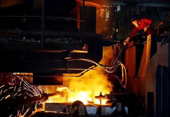 A worker tests the temperature of molten steel at a steel plant in Dalian, Liaoning province. (Photo by Liu Debin/For China Daily)