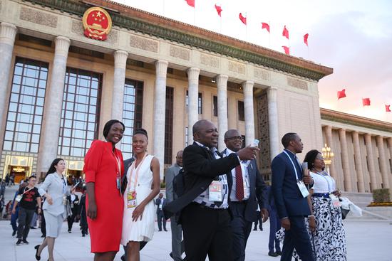 Country representatives (center and right) take in Tian'anmen Square with two journalists (left) in front of the Great Hall of the People in Beijing on Monday after the opening ceremony of the Beijing Summit of the Forum on China-Africa Cooperation. (ZOU HONG/CHINA DAILY)