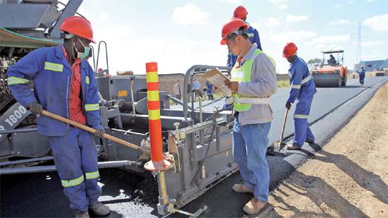   Local and Chinese workers in part of the way AVIC International, a state-owned Chinese company, was contracted to build in Lusaka, Zambia's capital. (Photo / China Daily) 